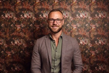 Portrait of a handsome man in a jacket and glasses on a floral background