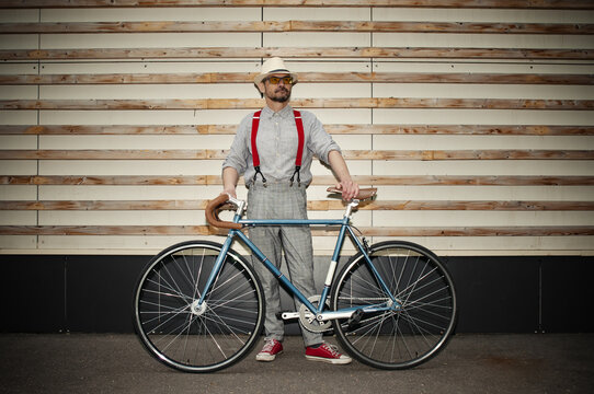 Adult hipster man with retro fixed gear bicycle on dark wall background