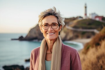 Fototapeta na wymiar Portrait of smiling senior woman with eyeglasses standing at seaside