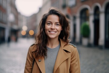 Fototapeta premium portrait of smiling young woman in autumn coat walking on city street