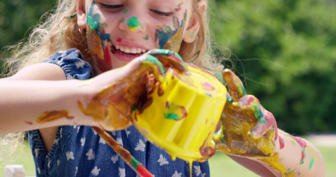 Child, face painting and play outdoor, having fun and happy for creative education. Park, art and girl with paint cup, brush and young kid smile, learning and enjoying quality time alone in nature