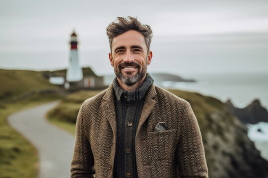Portrait of a handsome man standing in front of a lighthouse on a foggy day
