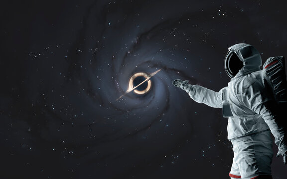 3D illustration of Astronaut looks at black hole and event horizon. 5K realistic science fiction art. Elements of image provided by Nasa