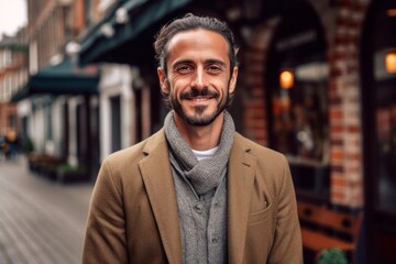 Fototapeta premium Portrait of handsome bearded man wearing coat and scarf looking at camera while standing outdoors