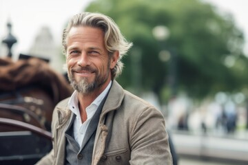 handsome middle aged man with grey hair smiling at camera in city