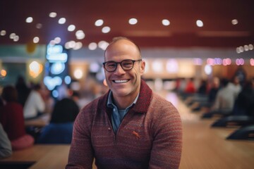 Fototapeta premium Portrait of happy mature man at bowling alley in club. Cheerful mature man looking at camera and smiling.