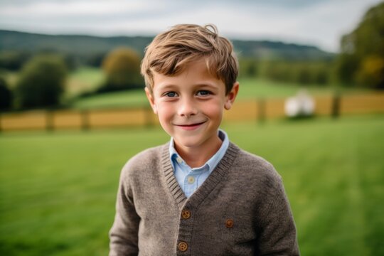 A portrait of a cute little boy outdoors in the countryside. He is smiling and looking at the camera.