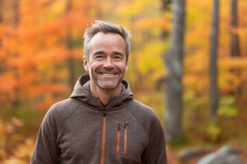 Naklejka na ściany i meble Portrait of a handsome middle-aged man smiling in an autumn forest