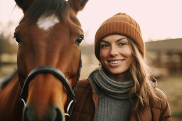 Fototapeta premium Medium shot portrait photography of a satisfied woman in her 30s that is wearing a cozy sweater against a beautiful horse ranch with riders taking lessons background . Generative AI