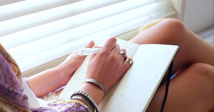 Planning, relax and a woman writing in a book for goals, creativity or reflection. Home, creative and closeup hands of a girl with a diary or notebook for notes, ideas or journaling in the morning