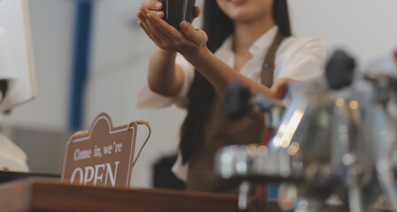 Open. barista, waitress woman wearing protection face mask turning open sign board on glass door in...