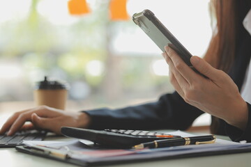 Portrait of Young Asian woman hand freelancer is working her job on computer tablet in modern office. Doing accounting analysis report real estate investment data, Financial and tax systems concept.