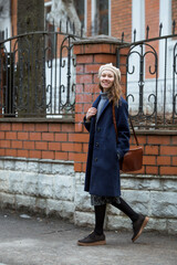 Portrait of a young woman over 30 years old in a beret and a stylish coat, a girl walks around the city in early spring. Modern lifestyle.