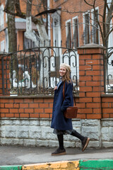 Portrait of a young woman over 30 years old in a beret and a stylish coat, a girl walks around the city in early spring. Modern lifestyle.