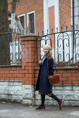 Portrait of a young woman over 30 years old in a beret and a stylish coat, a girl walks around the city in early spring. Modern lifestyle.