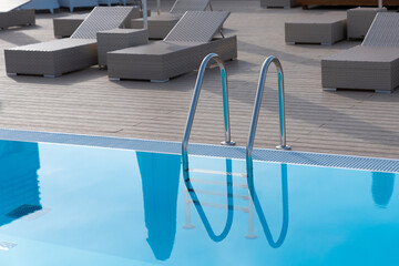Ladder stainless handrails for descent into swimming pool. Swimming pool with handrail.