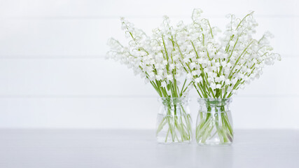 two bouquets of lilies of the valley on a white background close-up. background with lilies of the valley. lilies of the valley in vases and a copy of the space.
