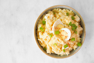 Traditional potato salad. Top down view on a white marble background.