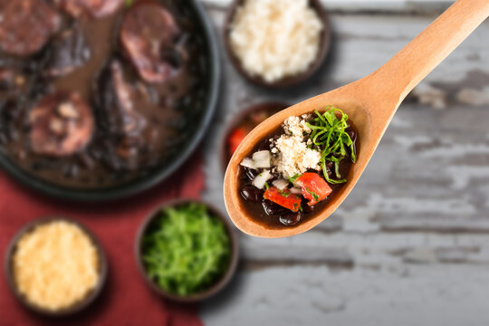 Selective focus on spoon with Brazilian Feijoada Food. Traditional Brazilian food made with black beans.