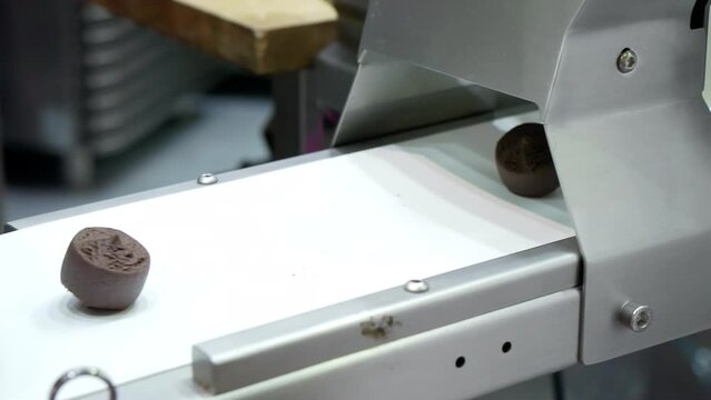 Candy factory. A special machine is stamping chocolates. Finished chocolates moving along a conveyor belt in a chocolate factory production line.