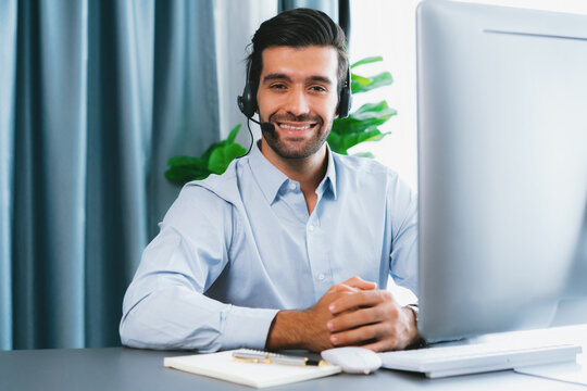 Male call center operator or telesales representative siting at his office desk wearing headset portrait. Customer service agent with smiling to camera on workplace. fervent