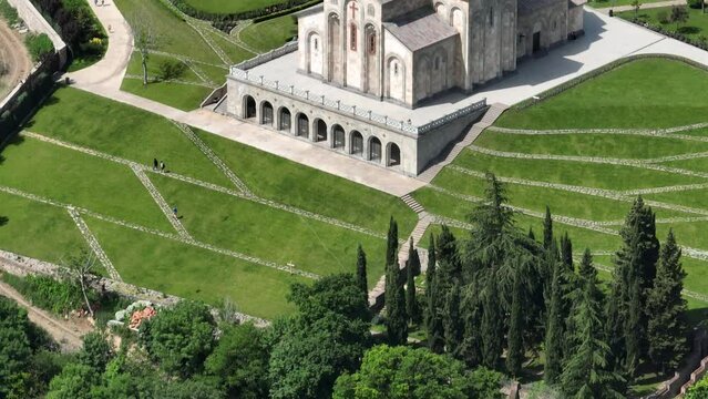 Aerial view of monastic complex of Bodbe nunnery on hillside among tall Cypress trees with Church of St. Nino on sunny day, Sighnaghi, Georgia