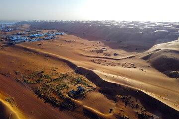 Aerial view of the sand dunes and village al Mintarib on sunny day. City on the edge of the desert. Sultanate of Oman
