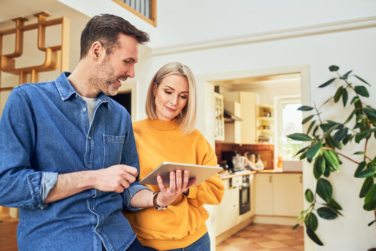 Mid adult couple at home planning new interior design with digital tablet