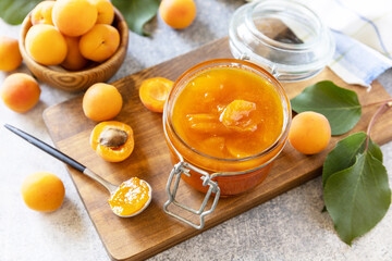 Homemade preservation. Delicious apricots jam or jelly on a stone table.