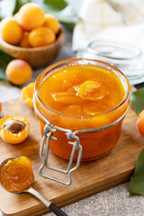 Homemade preservation. Delicious apricots jam or jelly on a stone table.