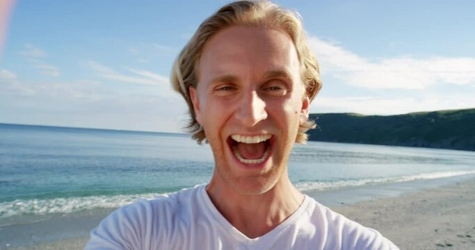 Man, wave and beach for video call, selfie or excited face with smile, tropical holiday or post vlog. Young influencer, content creator and outdoor for vacation, social network app or portrait by sea