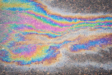 Petroleum fuel spilled on wet asphalt, abstract background