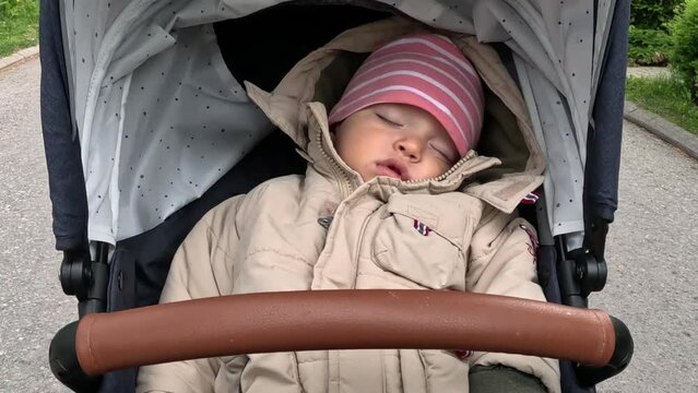 Baby boy sleeping in her pushchair stroller cradle while walking in the suburbs. Wide angle POV shot.