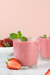 Strawberry smoothie or milkshake with berries on a pink background. Summer beverages. Copy space.