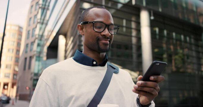 Phone, communication and a business black man walking in the city for networking on his morning commute. Mobile, contact and buildings with a male employee browsing or searching social media outside
