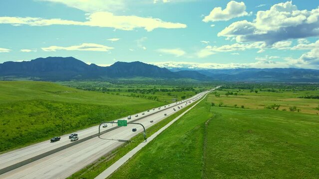 In this captivating drone shot, the camera glides effortlessly alongside the straight Highway 36 as it elegantly leads towards the enchanting city of Boulder, Colorado.