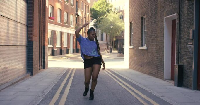 Young black woman, dancing and street in city with moving, steps and freedom with gen z fashion. African dancer girl, freestyle and vogue dance with attitude, confidence and celebration on metro road