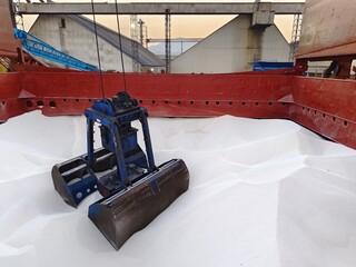 A grab is grabbing cargo in the hold of cargo ship or a bulk carrier during discharging operation