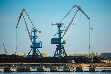 Fototapeta na wymiar Larger cranes in the port, cranes load bulk materials. The work of cranes in the seaport