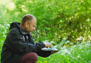 man 43 years old in the forest with a laptop