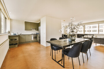 a kitchen and dining area in a house with wood flooring, white walls, and an open door leading to the living room