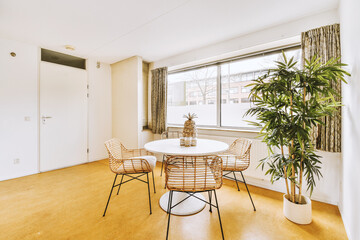 a dining room with chairs and a plant in the corner next to the window that looks out onto the street