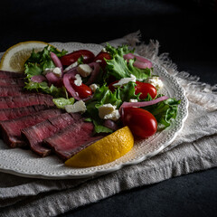 steak salad: medium rare grilled fillet mignon steak with mixed lettuce greens, pickled red onions, grape tomatoes, and crumbled feta cheese.