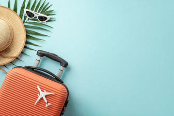 Summer getaway concept. Top view of an orange suitcase, small airplane figurine, beach essentials,...