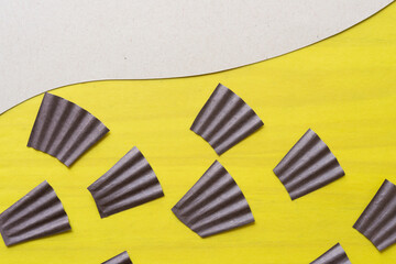 brown paper fans with folds on yellow and blank cardboard paper with wavy element