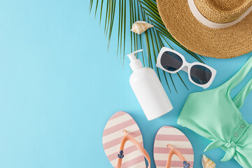 Sun protection cream concept on the beach. Top view flat lay of sunscreen bottle, swimsuit, bag, sun hat, flip flops, sunglasses, palm leaf and seashells on light blue background with space for ads