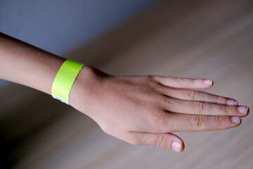 close-up of neon yellow paper bracelet on the male arm of child clinic patient, check tape with...
