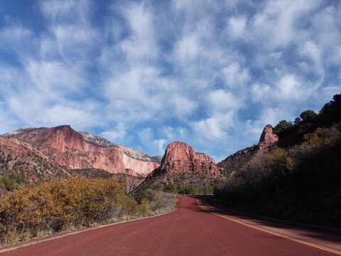 Red road to Zion National Park on a wispy cloudy day