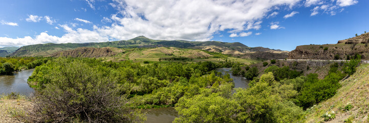 Fototapeta na wymiar Mtkvari river valley panorama in Samtskhe Javakheti region in Southern Georgia with lush green vegetation and Lesser Caucasus mountains in the background.