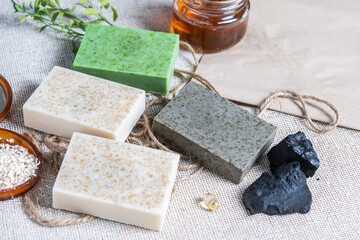 Fototapeta na wymiar Natural handmade soap bars with organic medicinal plants, rue plant, activated carbon, oatmeal. Homemade beauty products with honey, b vitamin and natural essential oils from plants and flowers.